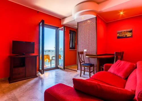 a living room with red walls and a red couch at MiraMare Residence Cefalú in Cefalù