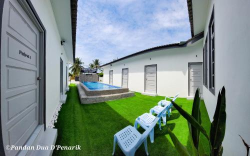 a yard with two white chairs and a swimming pool at Pandan Dua D'Penarik in Kampong Nyatoh