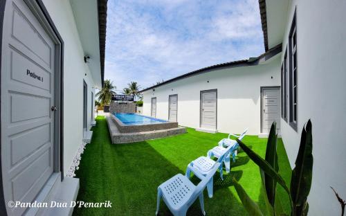 a yard with two white chairs and a swimming pool at Pandan Dua D'Penarik in Kampong Ru Sepuloh