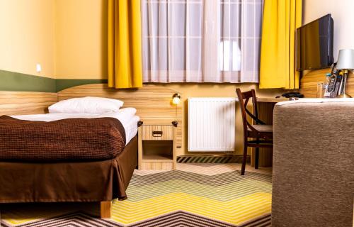 a bedroom with a bed and a desk with a television at Hotel Texas*** in Żory