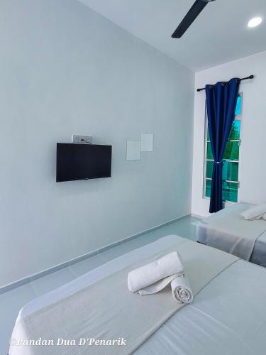 a white bedroom with two beds and a tv on the wall at Pandan Dua D'Penarik in Kampong Ru Sepuloh