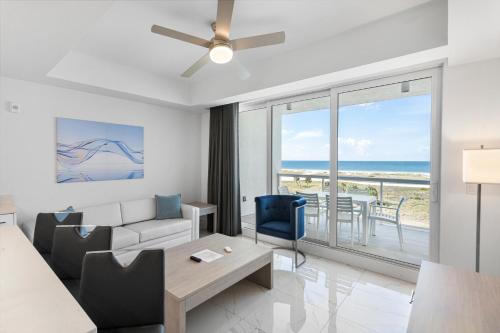 a living room with a couch and a ceiling fan at Ocean Club Treasure Island Hotel in St. Pete Beach