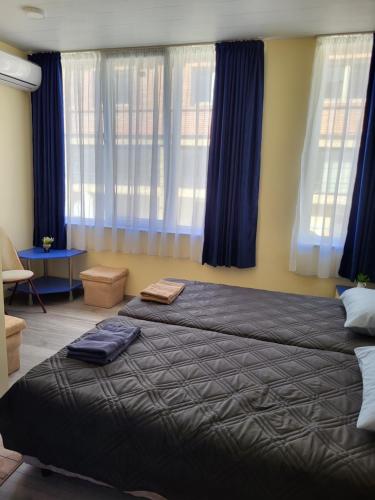 - une chambre avec 2 lits et des rideaux bleus dans l'établissement Къща за гости Бовъ с джакузи, à Gara Bov