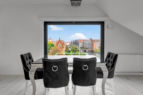 une table à manger avec des chaises et une grande fenêtre dans l'établissement Comfort Apartments Rezydencja Wintera, à Gdańsk