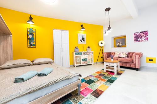 ein Schlafzimmer mit gelben Wänden, einem Bett und einem Sofa in der Unterkunft Apartman Paulina in Rovinj