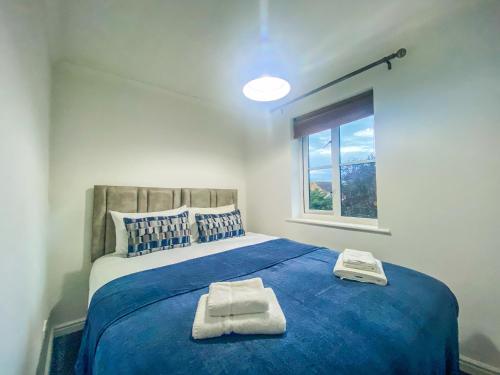 una camera da letto con un letto blu con due asciugamani di 3 Bedroom House by Elegance Living a Peterborough
