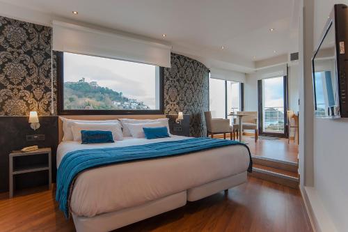 1 dormitorio con 1 cama grande y ventana grande en Sercotel Codina, en San Sebastián