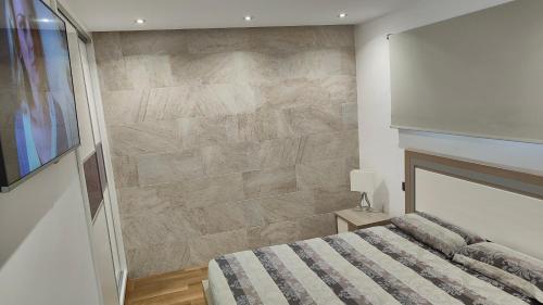 プラヤ・デル・イングレスにあるALAMO LUXURY APARTMENTのベッドと石の壁のある寝室