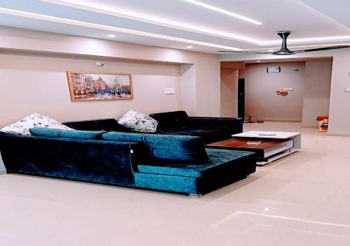 uma sala de estar com um sofá azul e uma mesa em Staeg Hill View 2BHK - 602 em Indore