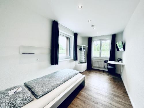 a white bedroom with a bed and two windows at Monteurzimmer - Worker's accommodation - ZIMMERzuVERMIETEN in Bäriswil in Bäriswil