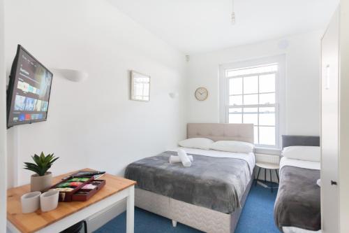 a bedroom with two beds and a table and a tv at Camden House in London