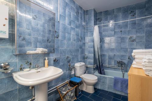 a blue tiled bathroom with a toilet and a sink at Palacete Fabian 1 in Ítrabo