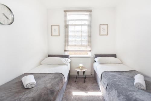 two twin beds in a room with a window at Camden House in London