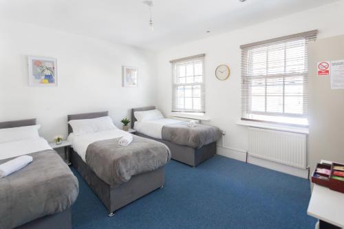 a room with two beds and two windows at Camden House in London
