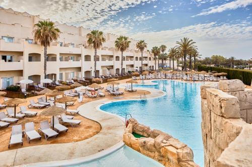 a resort pool with lounge chairs and palm trees at ALEGRIA Cabo De Gata in Retamar