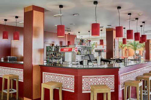 a bar in a restaurant with red walls and stools at ALEGRIA Cabo De Gata in Retamar