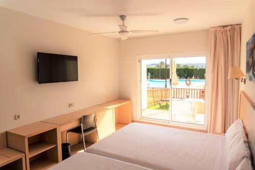 a bedroom with a bed and a desk and a window at ALEGRIA Cabo De Gata in Retamar