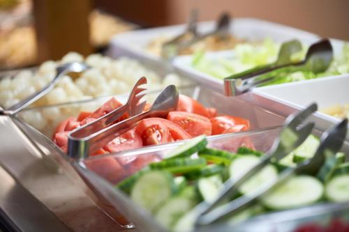 a buffet of food with tomatoes and cucumbers in plastic containers at ALEGRIA Cabo De Gata in Retamar