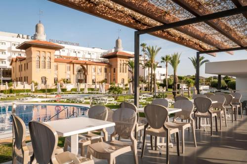 un patio con tavoli e sedie accanto alla piscina di ALEGRIA Palacio Mojacar - Adults Only a Mojácar