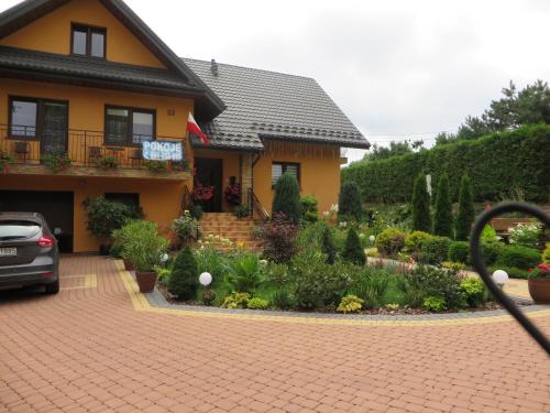 a house with a garden in front of it at Zielony Zakątek domki i pokoje 661-038-537 in Polańczyk