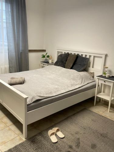 a white bed with two pillows and a pair of shoes at SleepWell1 in Cologne
