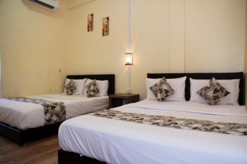 a bedroom with two beds with white sheets at Myra Hotel Mersing in Mersing