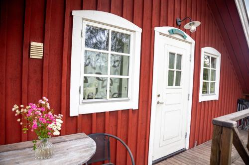 a red house with a wooden table with a vase of flowers at Ängagården - Gårdslyckan in Våxtorp