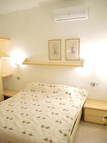 uma cama num quarto com duas fotografias na parede em Maison de vacances dans un village de vacances à100 m. de la plage em Badesi