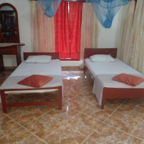 two beds in a room with red curtains at Grace Villa Bentota in Bentota
