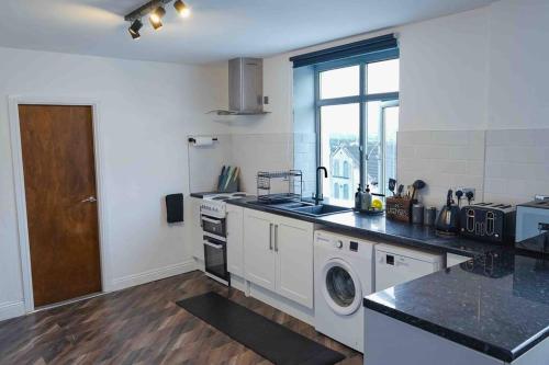 a kitchen with a sink and a washing machine at Stunning Two Bed City Centre Apartment in Hunslet