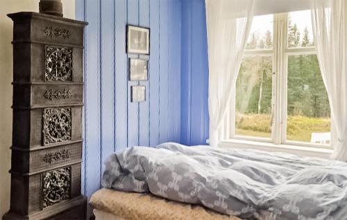 a blue bedroom with a bed and a window at Lovely Home In Hnefoss With House A Panoramic View in Hønefoss