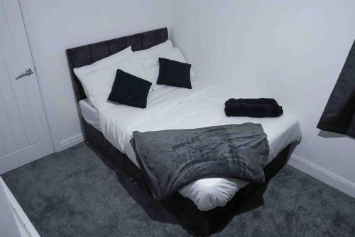 a bed with black and white sheets and pillows at Stunning Two Bed City Centre Apartment in Hunslet