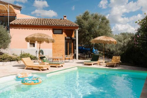 a swimming pool with chairs and umbrellas next to a house at Charmant Bas de Villa au cœur de la Provence in Manosque