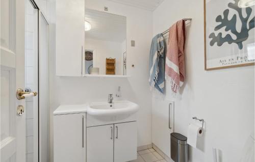 een witte badkamer met een wastafel en een spiegel bij Nice Home In Gudhjem With Kitchen in Gudhjem