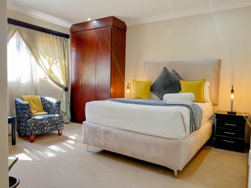 a bedroom with a large bed and a chair at Covesto Guesthouse - Waterkloof in Pretoria