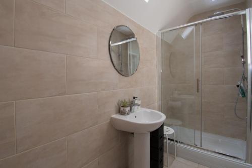 uma casa de banho com um lavatório, um chuveiro e um espelho. em Elegant and spacious private room with ensuite em Luton