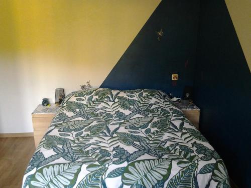 a bed with a green and white comforter in a bedroom at Chambre Cosy 1 séance de jacuzzi offerte in Hostun