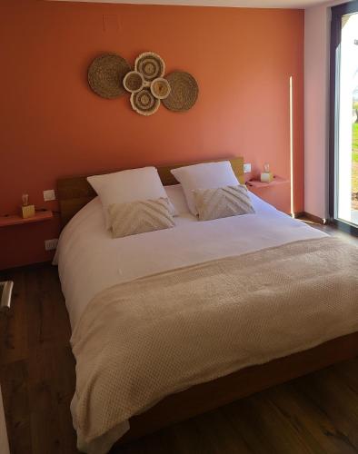 une chambre avec un grand lit aux murs orange dans l'établissement Au p'tit bonheur, à Rothbach