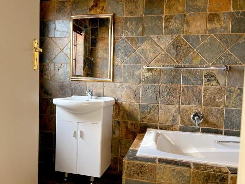 a bathroom with a sink and a bath tub at Covesto Guesthouse - Waterkloof in Pretoria
