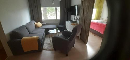 a living room with a couch and a chair and a bed at Huone Rauhallisessa Mummolassa in Kalajoki