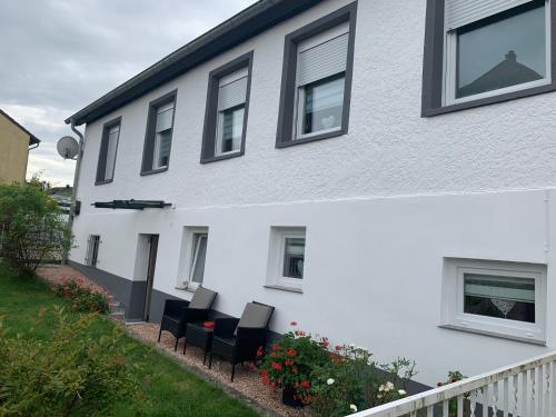 a white house with black chairs in front of it at Ferienwohnung Bella in Hühnerfeld