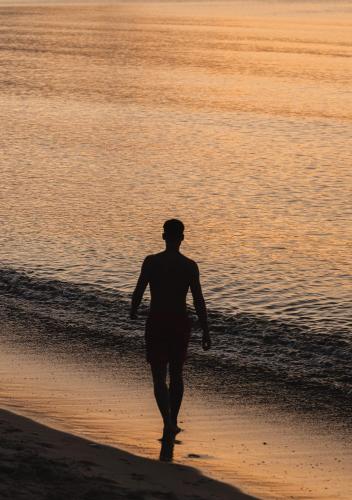 a man walking on the beach at sunset at ÖÖD Hötels Lohusalu LEIDA & ENNO in Laulasmaa