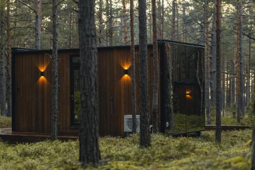 a wooden cabin in the woods with trees at ÖÖD Hötels Lohusalu LEIDA & ENNO in Laulasmaa