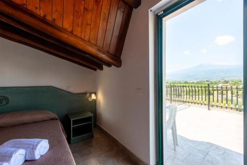 a bedroom with a bed and a balcony with a view at Villaggio Alkantara in Giardini Naxos