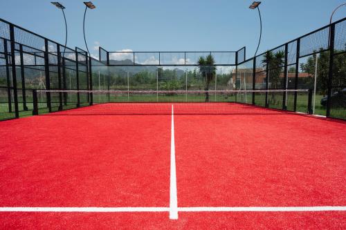 a tennis court with a red tennis court at Villaggio Alkantara in Giardini Naxos