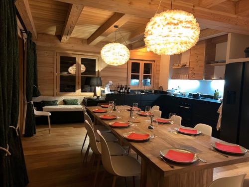 a dining room with a long table and a kitchen at Chalet Le Yéti de Villard 14 Prs - Domaine Alpe d'Huez - Bain nordique in Villard-Reculas