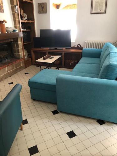 a living room with two blue couches and a tv at Gîte La grave haute sud in Mauzac-et-Grand-Castang