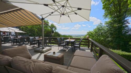 a patio with a couch and tables and an umbrella at Hostellerie Kemmelberg in Kemmel