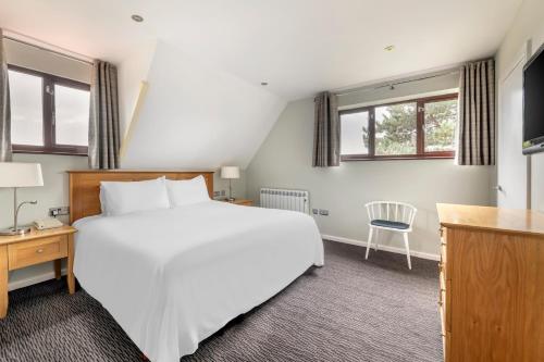 a bedroom with a large white bed and windows at Cromer Country Club in Cromer