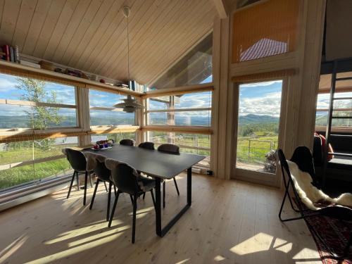 ein Esszimmer mit einem Tisch und Stühlen sowie großen Fenstern in der Unterkunft Veslestølen - Ålhytte with amazing view, 1000 meter in Ål